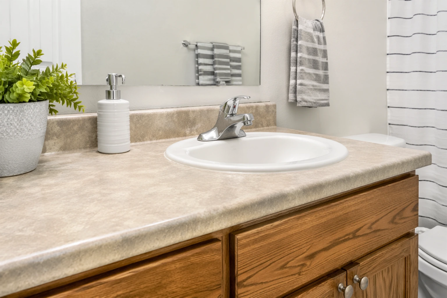 Bathroom vanity with laminate countertop, single sink, and wood cabinet in a simple, budget-friendly design